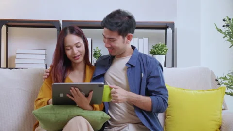 Young asian couple looking on tablet for relax with cozy and contentment si.. Vidéo 329456532