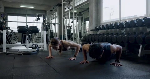 Young Asian couple performs push up exercise side by side on modern gym floor Stock Footage 337812867