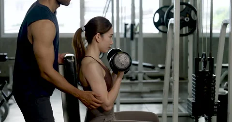 Young Asian couple practicing strength training in modern gym, man coaching Stock Footage 342584735