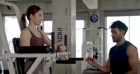 Young Asian couple sharing supportive gym coaching, woman rests on knee raise Stock Footage 338043316