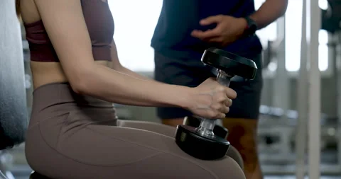 Young Asian couple training together in modern gym, woman seated lifting Stock Footage 338042997