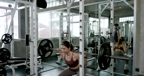 Young Asian couple working out together in modern gym, woman performs barbell Stock Footage 338043451