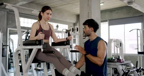 Young Asian couple working out in modern gym, woman lifts legs on knee raise 動画素材 342586766