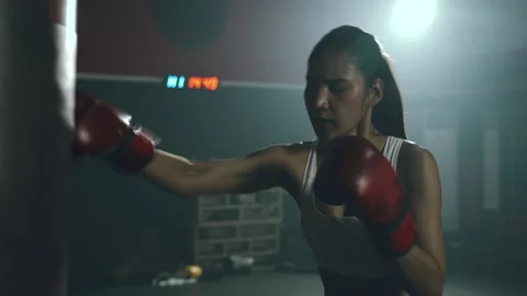 Young Asian doing boxing or Muay Thai punching sandbag in fitness club or gym Stock Footage 151607527