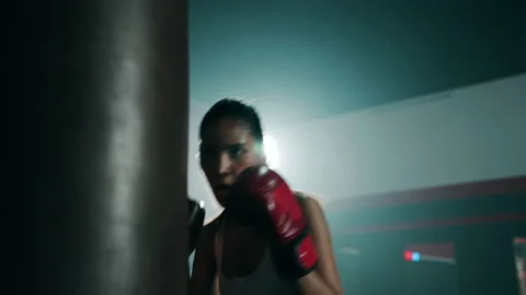 Young Asian doing boxing or Muay Thai punching sandbag in fitness club or gym Stock Footage 151607706
