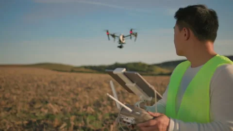 Young asian engineer with digital tablet flying black drone over field Stock Footage 162971017