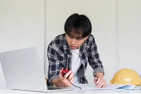 Young Asian engineer drawing construction project plans on plan paper on table Stock Photos