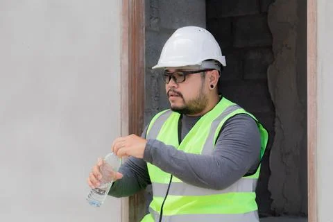 Young Asian engineering worker overweight employee foreman thirsty drinking.. Stock Photos
