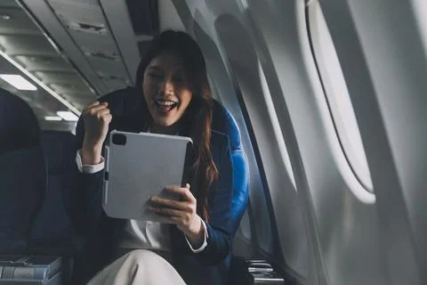 Young Asian executive excels in first class, multitasking with digital tabl.. Stock Photos