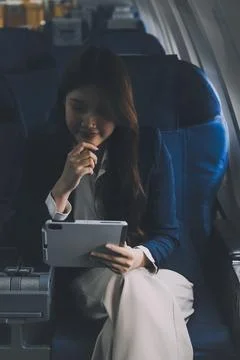 Young Asian executive excels in first class, multitasking with digital tabl.. Stock Photos