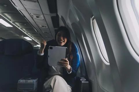 Young Asian executive excels in first class, multitasking with digital tabl.. Stock Photos