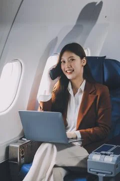 .Young Asian executive excels in first class, multitasking with digital tab.. Stock Photos