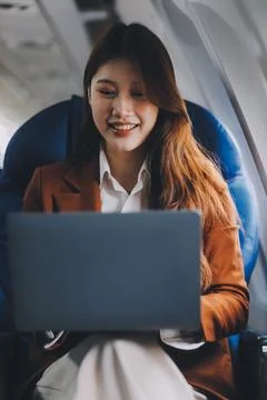 .Young Asian executive excels in first class, multitasking with digital tab.. Stock Photos