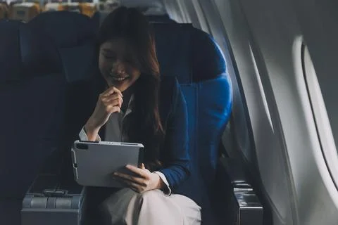 Young Asian executive excels in first class, multitasking with digital tabl.. Stock Photos