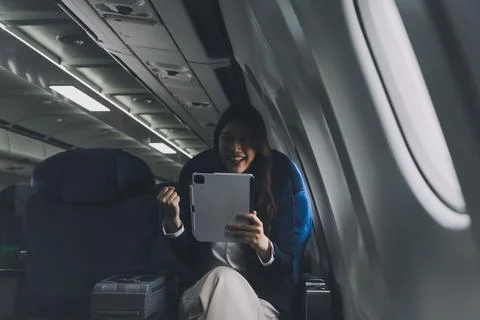 Young Asian executive excels in first class, multitasking with digital tabl.. Stock Photos