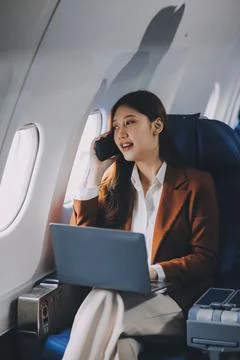 .Young Asian executive excels in first class, multitasking with digital tab.. Stock Photos