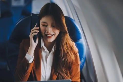 .Young Asian executive excels in first class, multitasking with digital tab.. Stock Photos