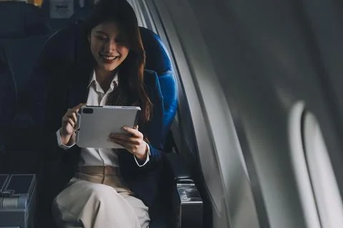 Young Asian executive excels in first class, multitasking with digital tabl.. Stock Photos