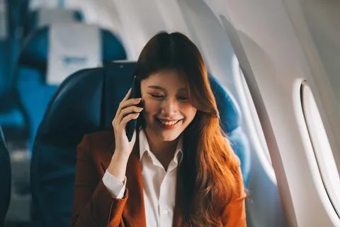 .Young Asian executive excels in first class, multitasking with digital tab.. Stock Photos