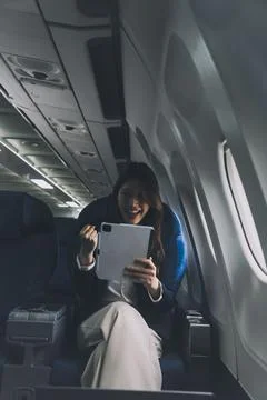 Young Asian executive excels in first class, multitasking with digital tabl.. Stock Photos