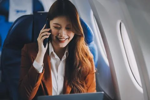.Young Asian executive excels in first class, multitasking with digital tab.. Stock Photos