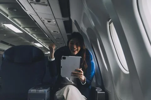 Young Asian executive excels in first class, multitasking with digital tabl.. Stock Photos