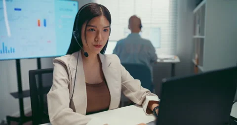 Young Asian female agent talking on phone headset consulting client online. Stock Footage 340814848