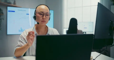 Young Asian female agent talking on phone headset consulting client online. Stock Footage 340814893