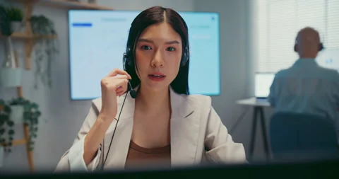 Young Asian female agent talking on phone headset consulting client online. Stock Footage 340815230
