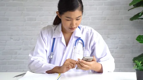 Young Asian female Doctor using a mobile phone at hospital. Healthcare worker Stock Footage