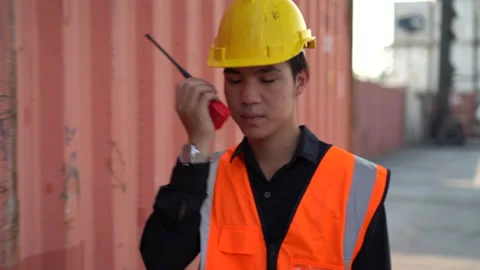Young asian foreman walking and talking on the walkie-talkie control loading Stock Footage 157715153