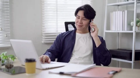 Young Asian freelance professional multitasking with phone call and laptop .. Stock Footage 337650551