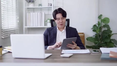 Young Asian freelance professional using digital tablet reviewing project d.. Stock Footage 337650381