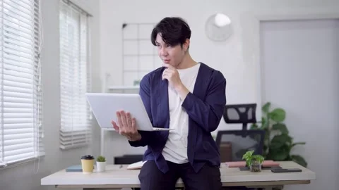 Young Asian freelancer working on laptop while sitting on desk in modern mi.. Stock Footage 337650706