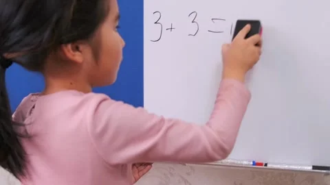 Young Asian girl erasing math equation on whiteboard at home, correcting Stock Footage 333483704