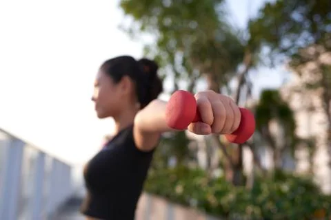Young Asian girl excercising with dumbbell outdoor to saty fit. Stock Photos