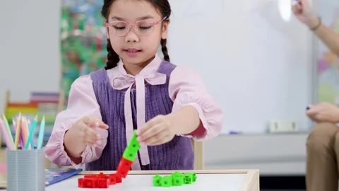Young Asian Girl Learning Math with Colorful Plastic Counting Cubes Stock Footage 328623297