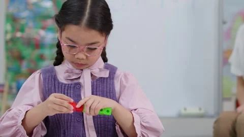 Young Asian Girl Learning Math by Connecting Colorful Plastic Cubes Stock Footage 328623321