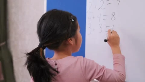 Young Asian girl solving math problems on whiteboard at home, early education Stock Footage 333483702