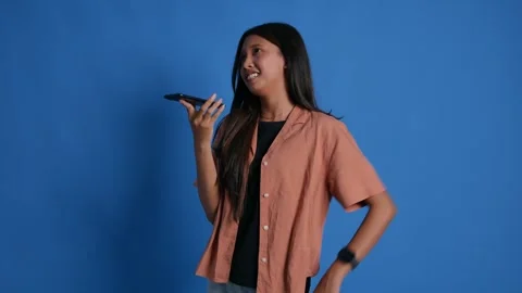 Young Asian girl standing while on phone with loud speaker mode. Isolated on Stock Footage 337970361