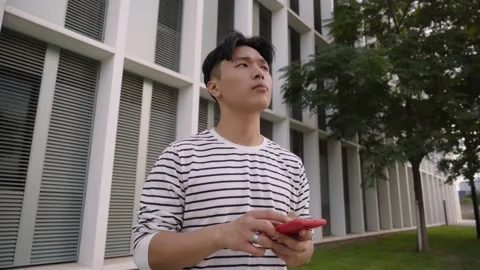 Young Asian guy navigating with mobile apps on a phone reading digital maps Stock Footage 213677846