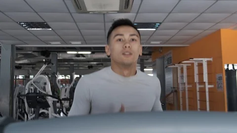 Young Asian guy is running on a treadmill in a gym. Stock Footage 114291296
