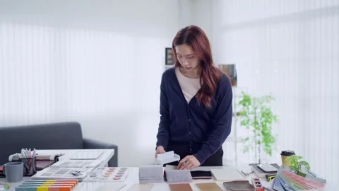 Young Asian interior designer examines fabric swatches and color samples at.. Stock Footage 345148997