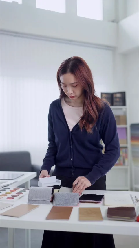 Young Asian interior designer examines fabric swatches and miniature sofa m.. Stock Footage 345149020
