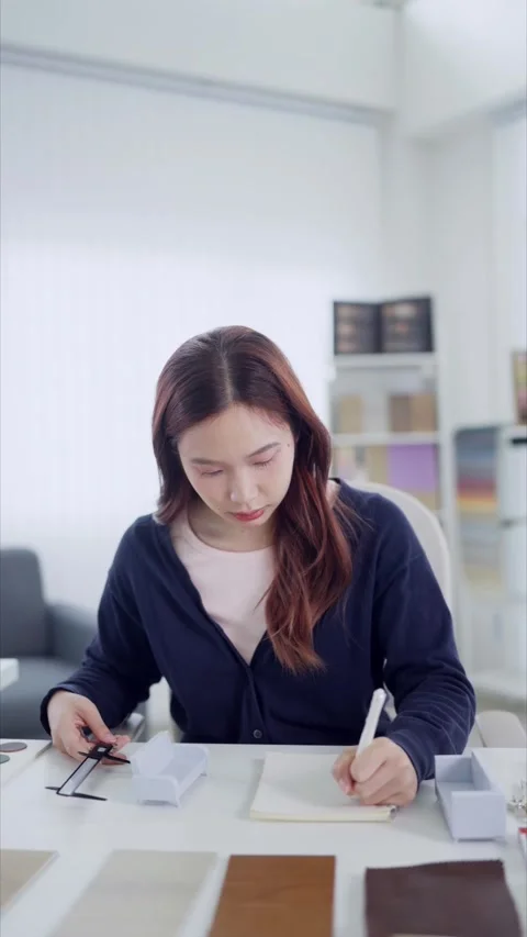 Young Asian interior designer writing notes while examining material swatch.. Stock Footage 345149075
