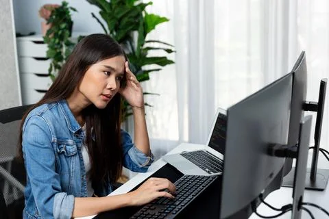 Young Asian IT developer analyzing software on pc screens and laptop. Stratagem. Foto stock