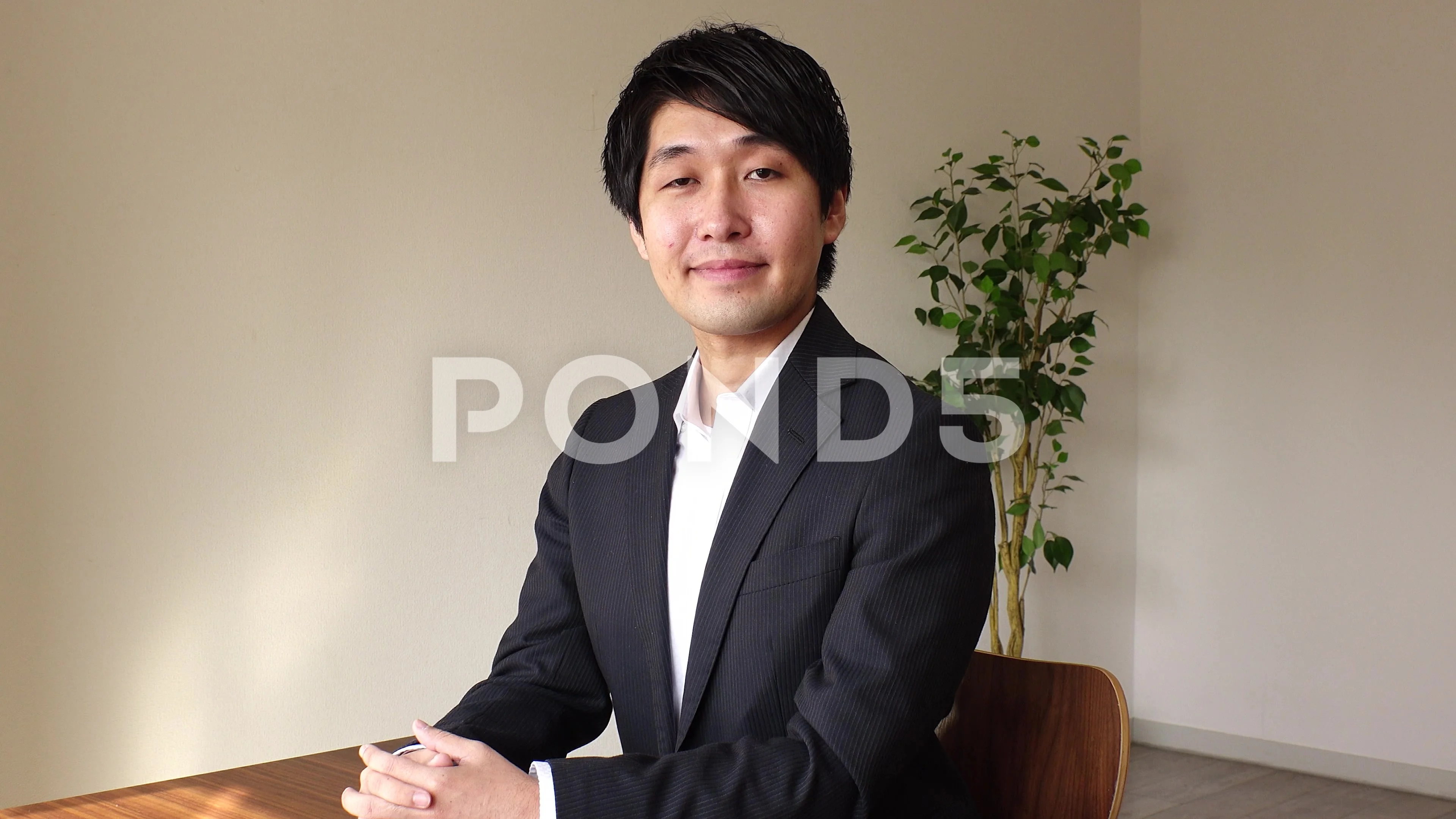 Man, with long black hair, wearing black suit, has a japanese