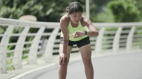 Young asian jogger checking time upon finishing running Stock Footage 271610958