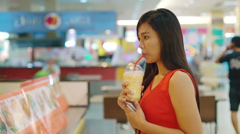 Young Asian Lady drinking fruit shake in food court Stock Footage 63883420