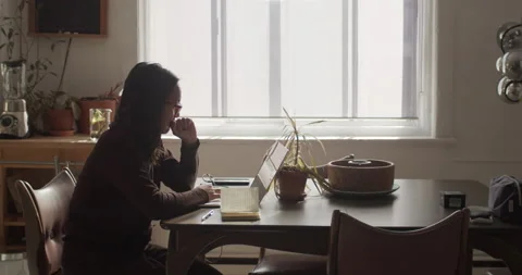 A young asian lady works at her laptop computer in a rustic apartment Stock Footage